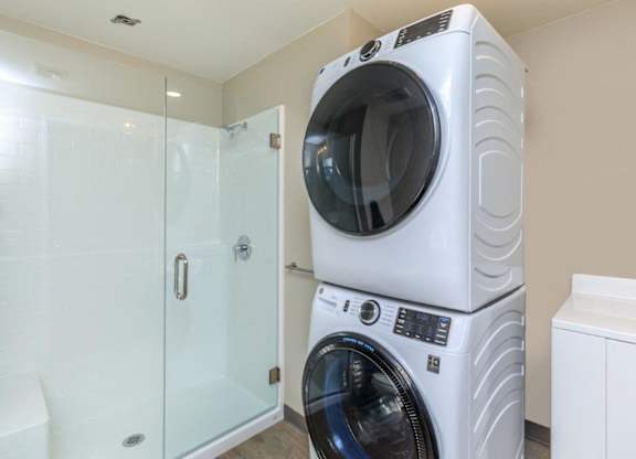 A white front load washing machine in a laundry room.