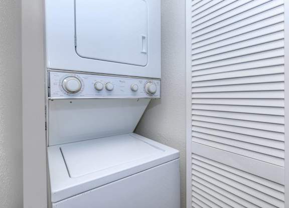 A white oven with a white door and white controls is next to a white wall with horizontal lines.