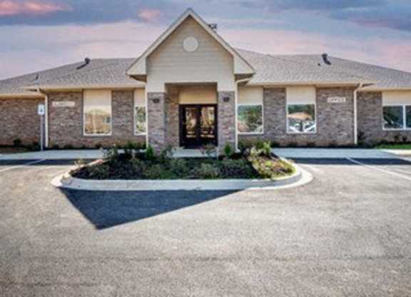 A building with a front yard and a driveway in front.
