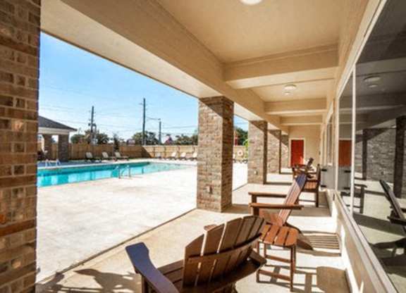 A patio with chairs and a pool in the background.