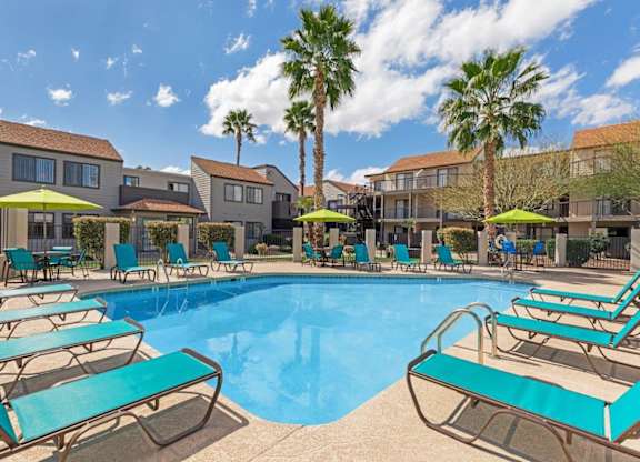 A pool surrounded by sun loungers and palm trees.