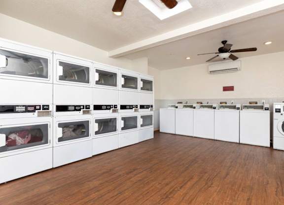 A laundry room with a row of washers and dryers.