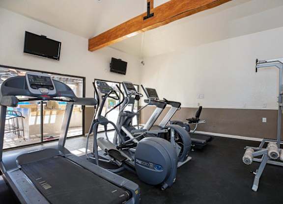 A gym with treadmills, exercise bikes, and a television.