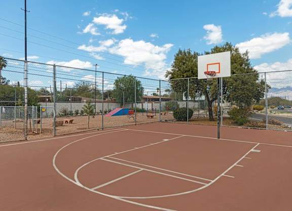 A basketball court with a basketball hoop and a fence surrounding it.
