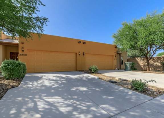 A house with a yellow garage door and a driveway leading to it.