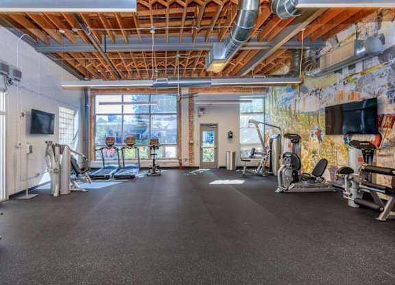 A gym with a variety of equipment including treadmills, weights, and exercise machines.