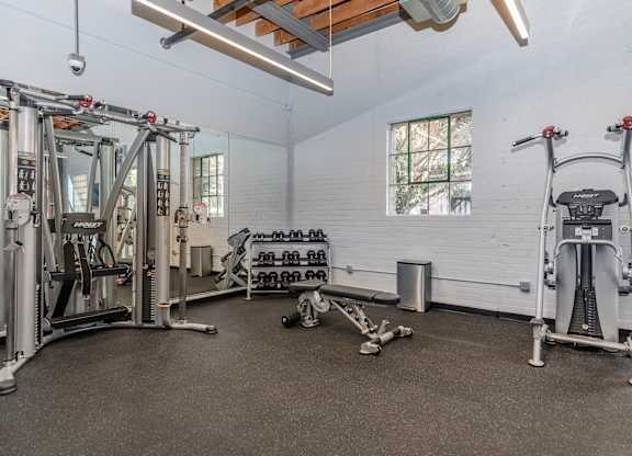 A gym with a variety of equipment including a leg press machine, a chest press machine, and a squat rack.