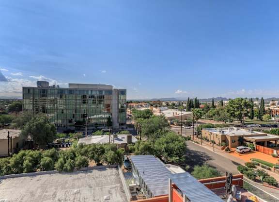 A modern building with a glass facade is the focal point of a sunny, clear day in a suburban area.