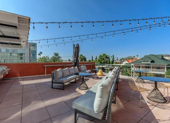 A patio with a string of lights and a few chairs and tables.