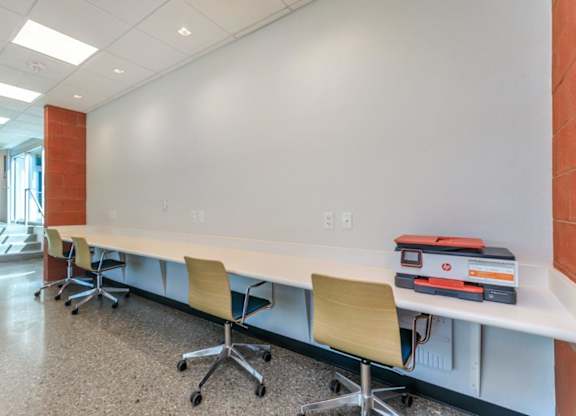 A long white table with chairs and binders on it.