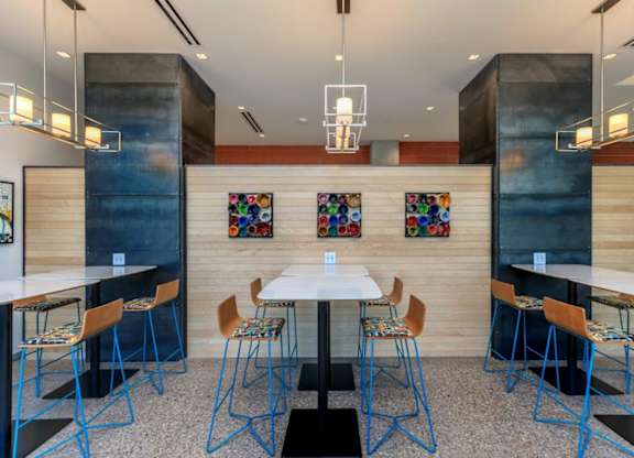 A modern dining area with a white table and blue chairs.