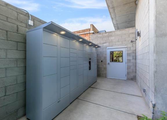 A grey storage unit is in a concrete courtyard.