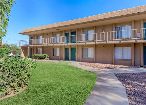 A sunny day at the apartment complex with green grass and bushes.