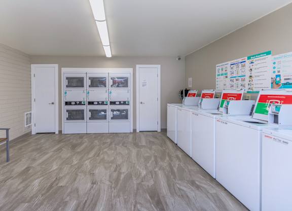 A room with white cabinets and a wall of fridges.