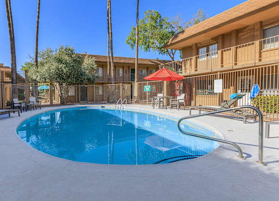 A swimming pool in a resort with a red umbrella.