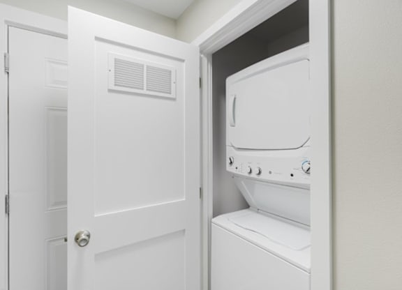 A white door is open to a white dryer.