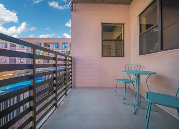 A balcony with a table and chairs overlooking a pool.