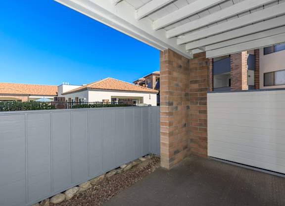 A white fence with a brick pillar in front of a garage.