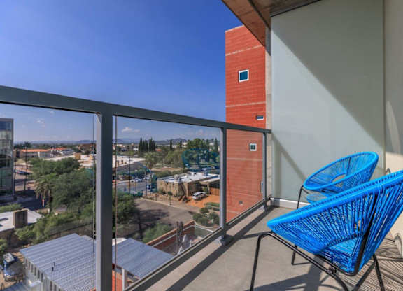 A balcony with a blue chair and a view of the city.