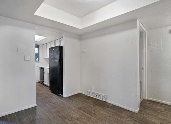 A kitchen with a black fridge and wooden floors.