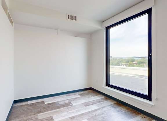 A room with a large window and a wooden floor.