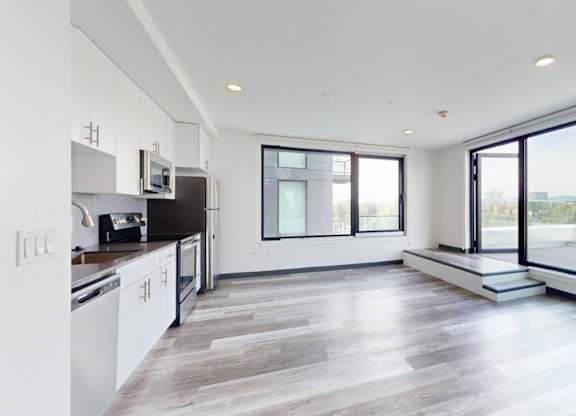 A modern kitchen with white cabinets and a large window overlooking the landscape.