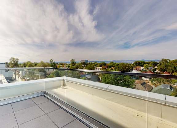 A balcony with glass railings overlooks a residential area.