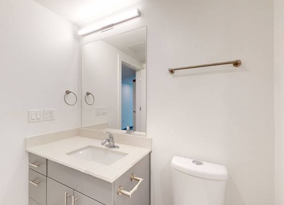A white bathroom with a sink, toilet, and mirror.