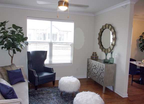 A living room with a blue chair and a white ottoman.