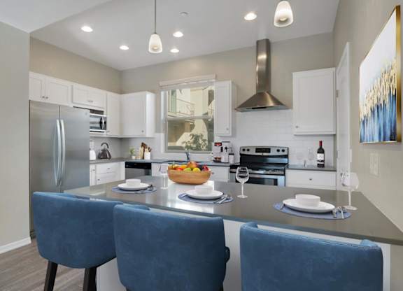 A modern kitchen with a large island and blue chairs.