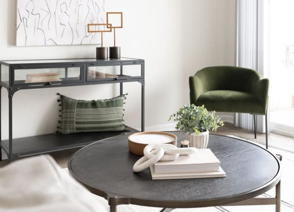 a round black table with a stack of books on it and a green chair in the background