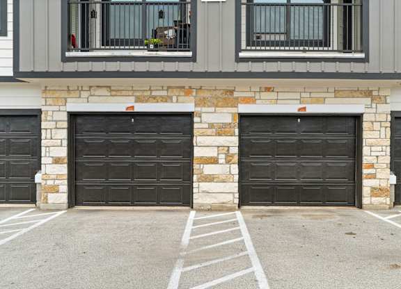 A house with two black garage doors and a stone pillar in the middle.