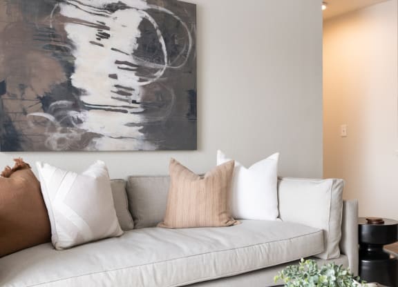 a living room with a gray couch and a black and white painting on the wall