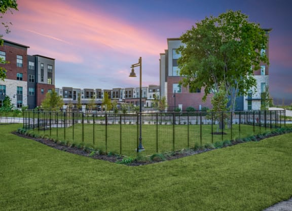 a park with a fence in front of an apartment building