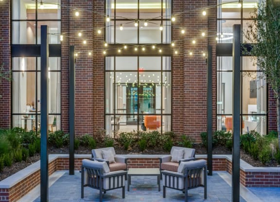 a patio with chairs and tables in front of a building