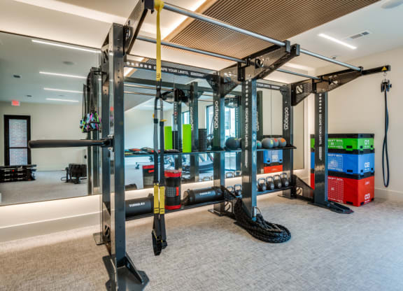 a gym with weights and other gym equipment in a room with a large mirror