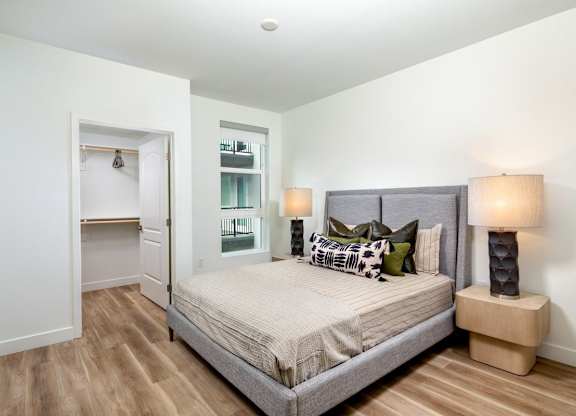 A bedroom with a large bed and a nightstand with a lamp.