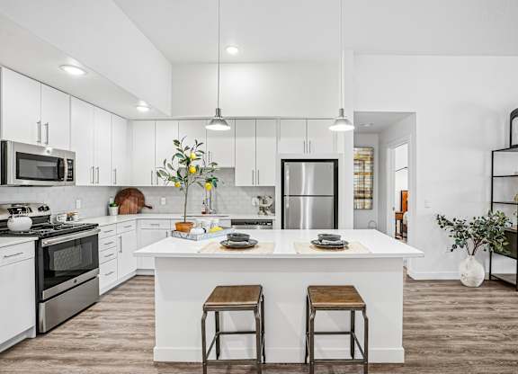 A modern kitchen with a white island and stools.