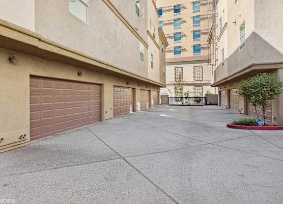 A long, narrow driveway between two buildings with garage doors.