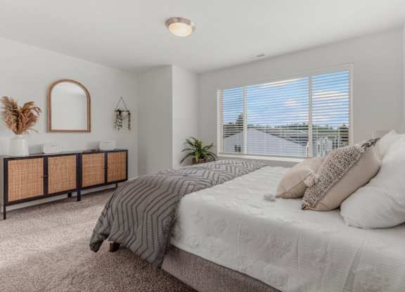 A bedroom with a large bed and a window with blinds.