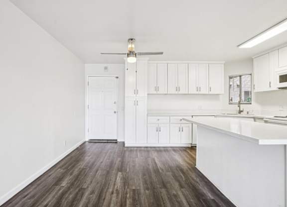 A kitchen with white cabinets and a wooden floor.