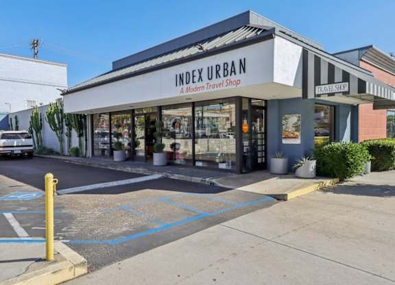 A modern travel shop named Index Urban is located in a parking lot.