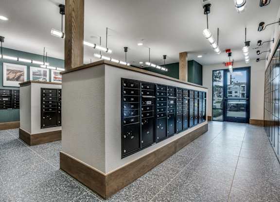 A row of black vending machines are lined up in a room with a tiled floor.