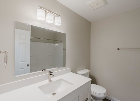 A white bathroom with a toilet, sink, and mirror.