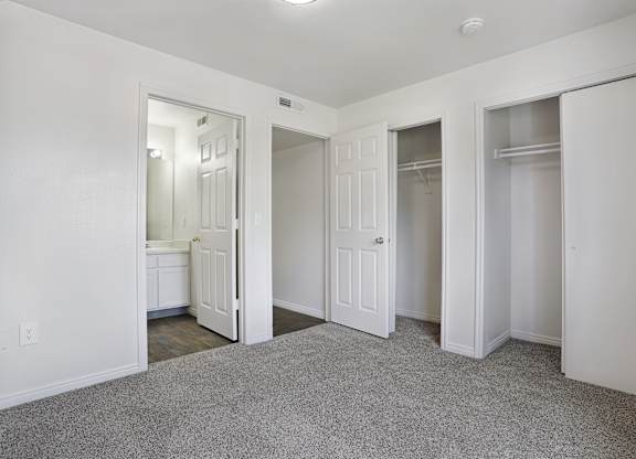 A white room with a carpeted floor and three open doors.