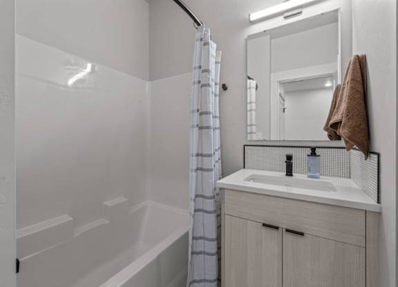 A white bathroom with a striped shower curtain.