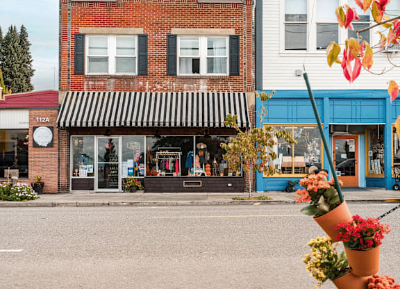 A flower pot is in the foreground of a street scene with a storefront in the background.