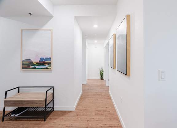 A long hallway with a bench and pictures on the wall.