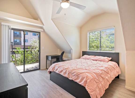 A bedroom with a bed, a chair, and a ceiling fan.
