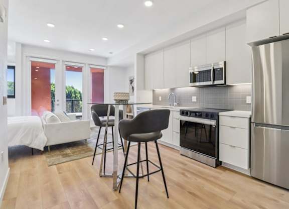 A modern kitchen with white cabinets and a wooden floor.